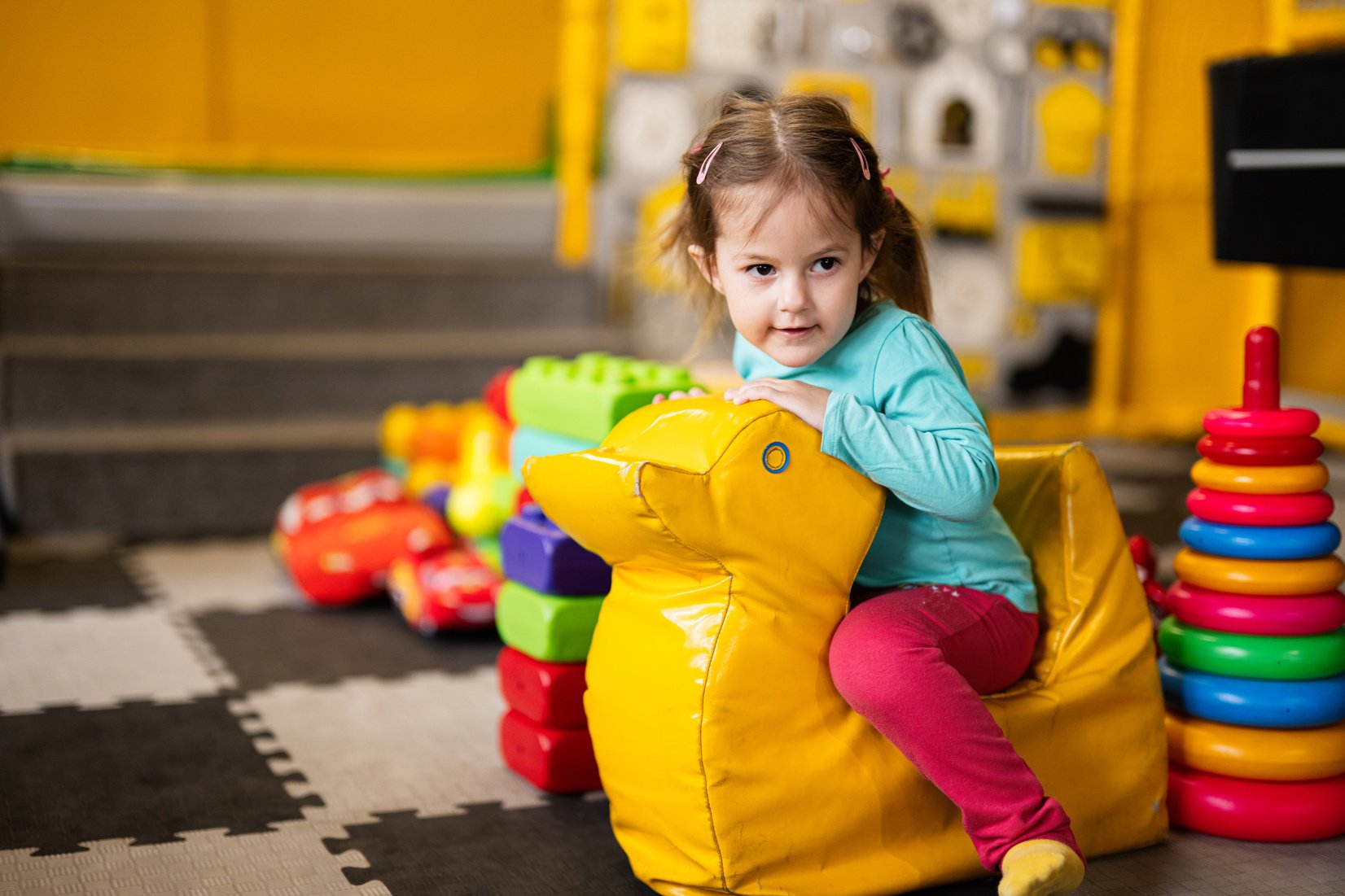 Baby girl swings on yellow paralon duck at kindergarten.